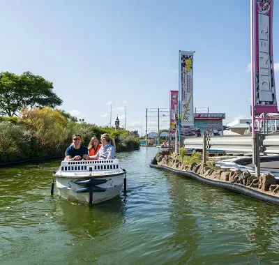 A family steering a replica mini boat along the Skegness canal