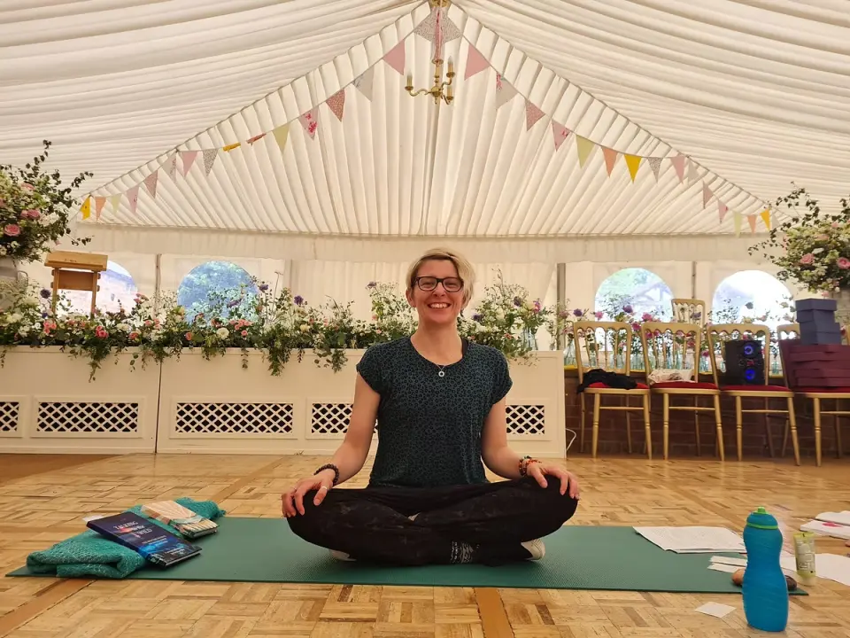 Steph from So..Yoga sitting cross-legged on a yoga mat